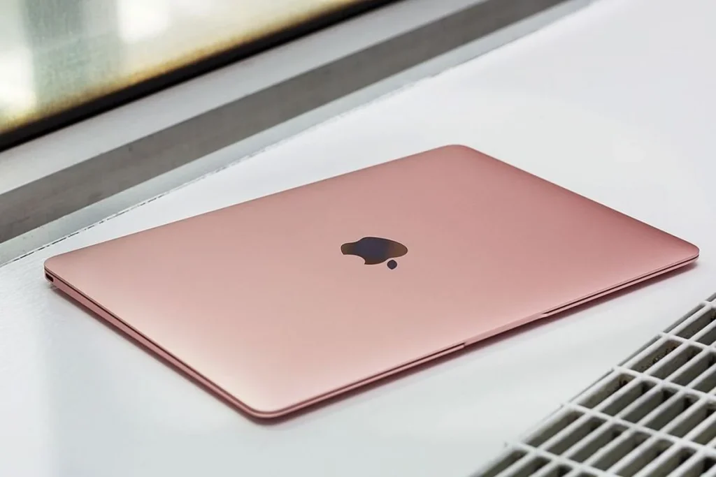 Top 10 Laptop Brands in 2026.A closed, rose gold Apple MacBook resting on a clean, white surface near a window.